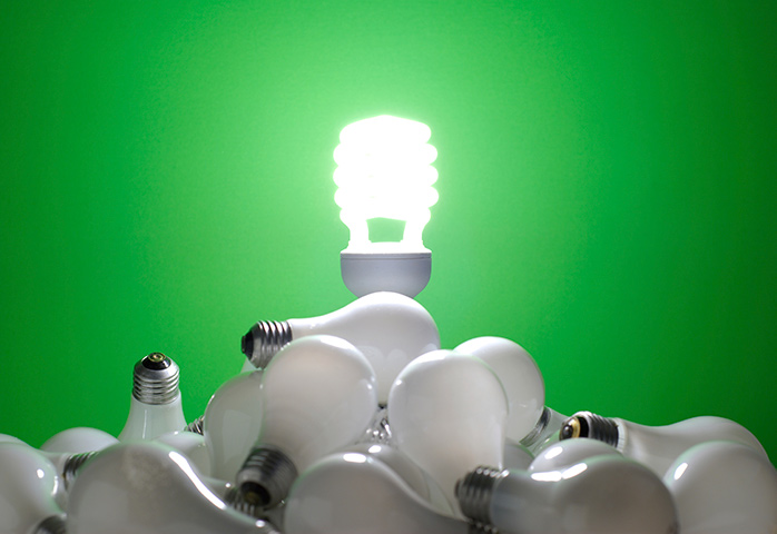Energy efficient lightbulb standing victorious over old incandescent bulbs