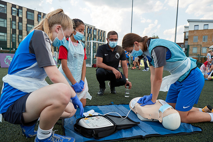 Dr Zaf Iqbal with participants from AFC Wimbledon's PL Kicks Programme during a CPR training session