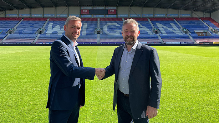 Two men shaking hands on Wigan's football pitch