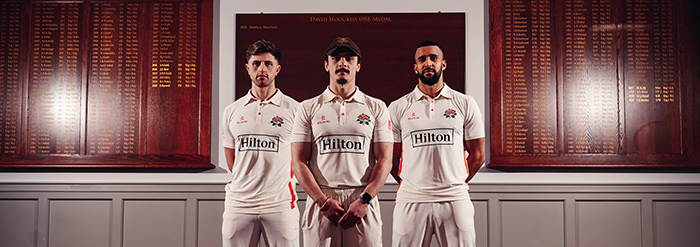 Three players from Lancashire Cricket wearing Hilton-branded County Championship shirts