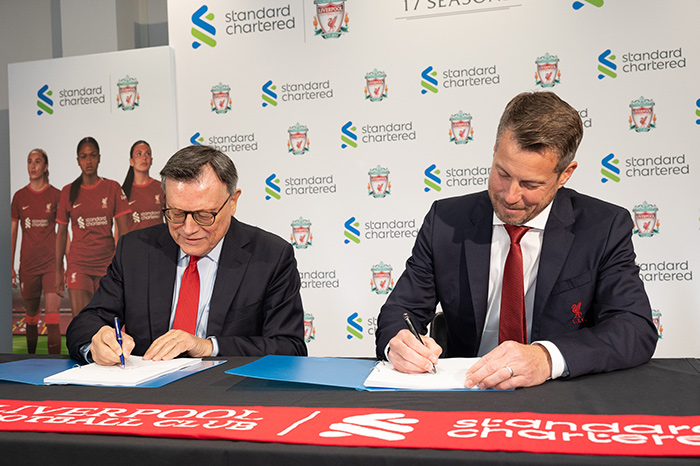 Liverpool Football Club and Standard Chartered Bank signing their partnership contract