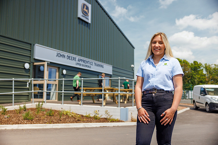 Honor Miles, an Apprentice Technician, stands in front of the new John Deere Training Centre.