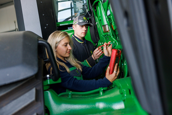 Two John Deere apprentices working on a machine during their apprenticeship course.