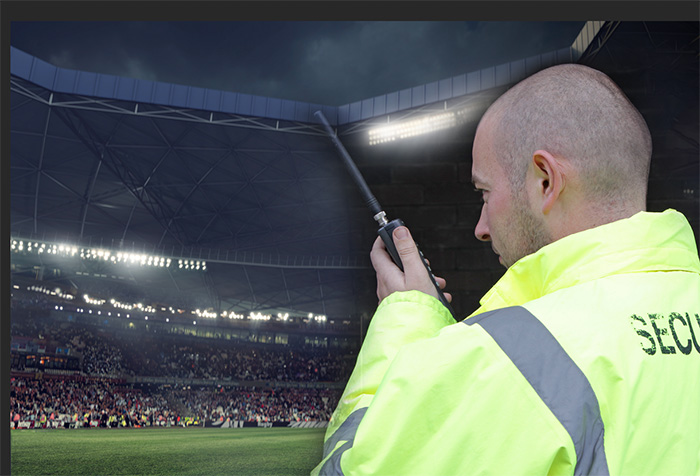A security officer at a stadium match using a Hytera radio