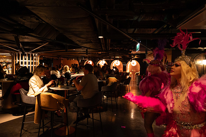 People dining at The Mezz, with a dance performance in the background