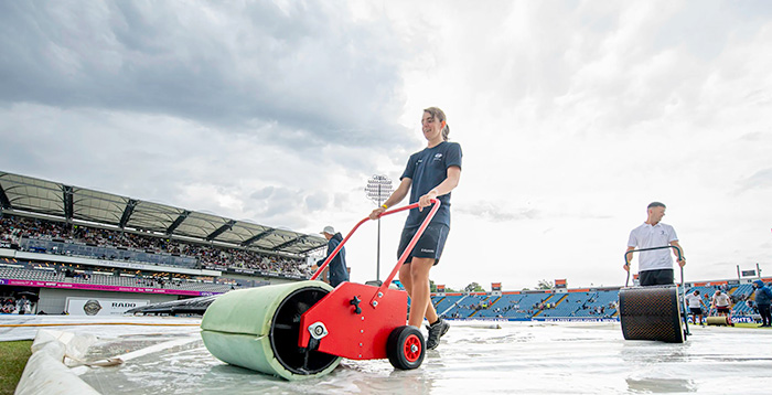 Jasmine Nicholls and team clearing the water from the pitch at Headingley