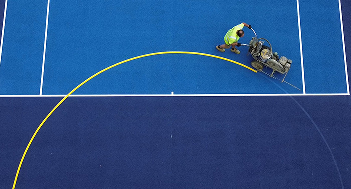 A Jointline operative applying line markings to a sports court
