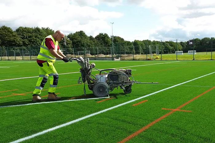 A Jointline operative applying line markings to a sports pitch