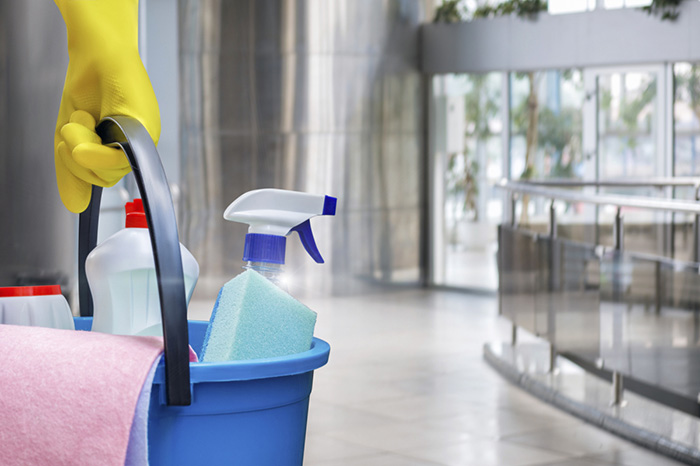 A cleaner with a bucket containing assorted cleaning products