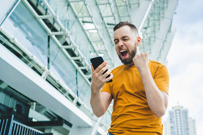 A cheering fan in a stadium looking at his mobile